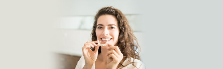A woman holding invisalign braces in hand