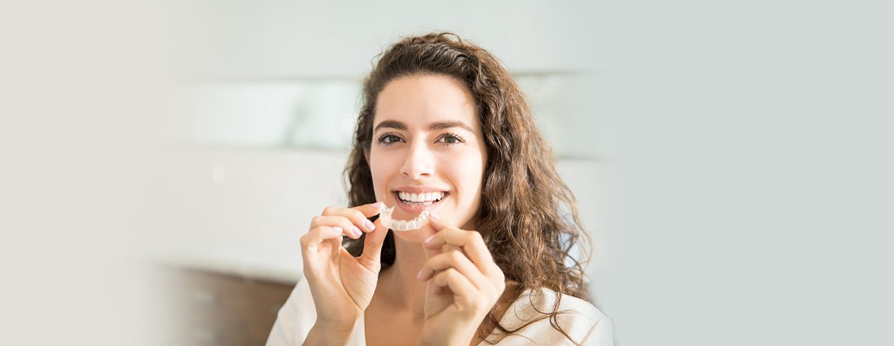 A woman holding invisalign braces in hand